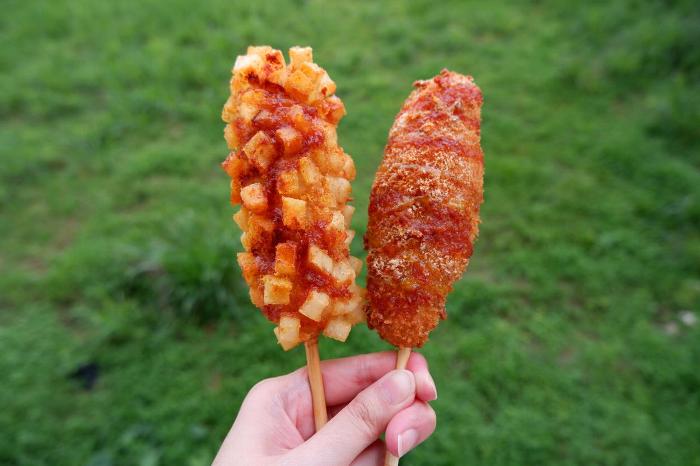 Someone holding two Korean corndogs